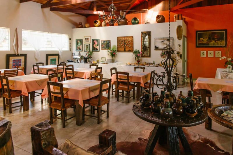 Salão do café da manhã com mesas de madeira e decoração rústica