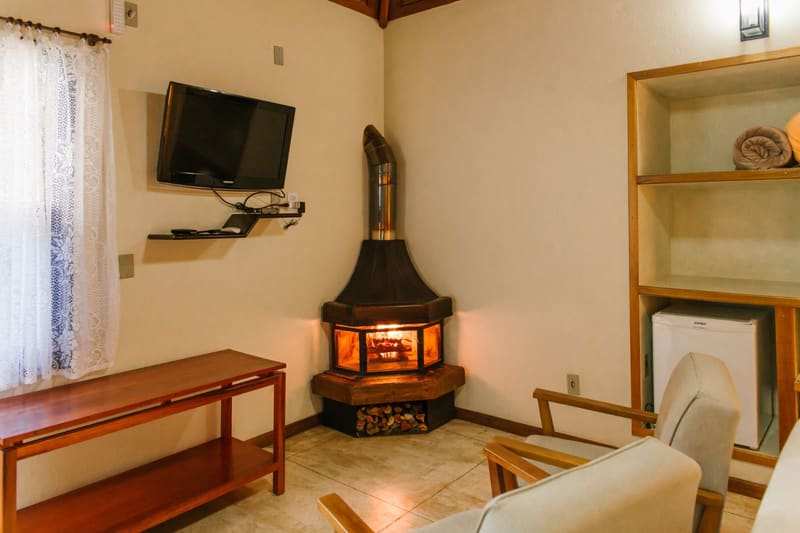 Sala de chalé com lareira acesa e poltronas