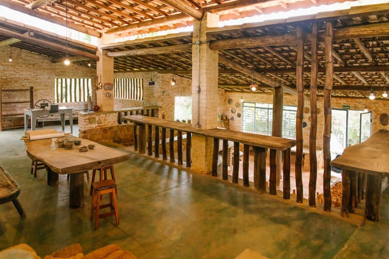 Espaço coberto de convivência com mesas rústicas de madeira