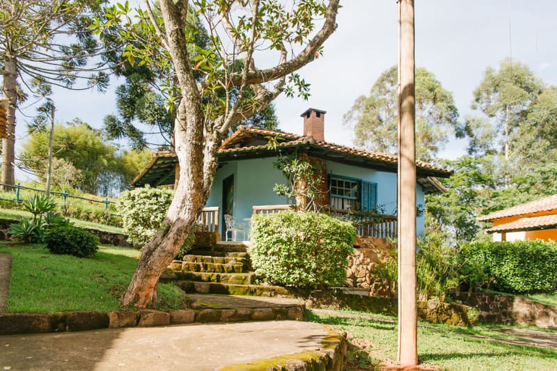Chalé azul da Pousada Cheiro da Terra entre árvores e jardins, em Cunha (SP)